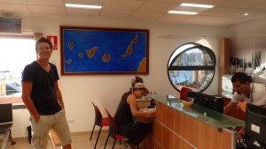 Terese ved at udfylde papirer på havnekontoret, Martin foran kort over canariske øer