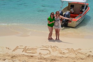 Emilie og Clara skriver "Hej DK" i sandet